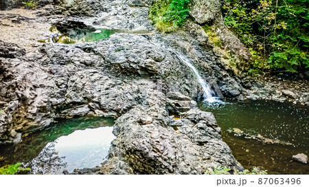 A small and cute waterfall flowing through the rocks 87063496