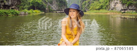 BANNER, LONG FORMAT Woman tourist in boat on the lake Tam Coc, Ninh Binh, Viet nam. It's is UNESCO World Heritage Site, renowned for its boat cave tours. It's Halong Bay on land of Vietnam. Vietnam 87065585