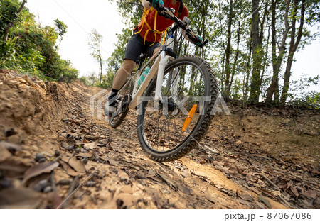 Woman riding bike on mountain top forest trail 87067086