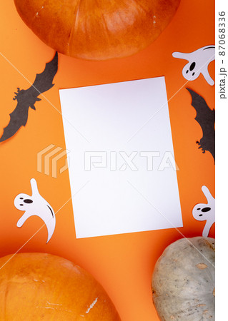 Composition of halloween decoration with pumpkin and sheet with copy space on orange background 87068336