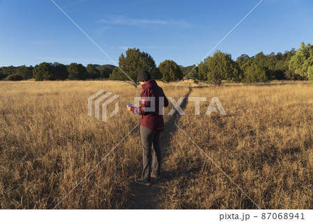 USA, New Mexico, Silver City, Woman o footpath crossing grassy field looking at map USA, New Mexico, Silver City, Woman o footpath crossing grassy field looking at map 87068941