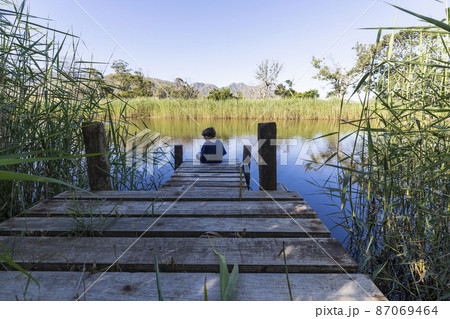 South Africa, Stanford, Boy (8-9) sitting on wooden pier 87069464