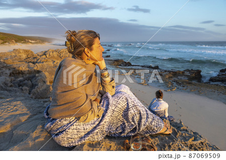 South Africa, Western Cape, Woman sitting on beach looking at ocean in Lekkerwater Nature Reserve South Africa, Western Cape, Woman sitting on beach looking at ocean in Lekkerwater Nature Reserve 87069509