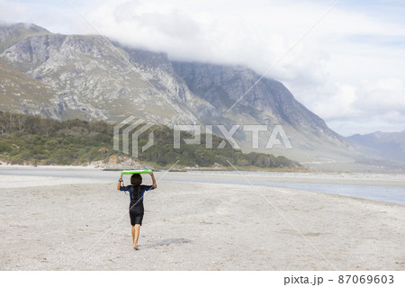 South Africa, Hermanus, Boy (8-9) carrying bodyboard on beach South Africa, Hermanus, Boy (8-9) carrying bodyboard on beach 87069603