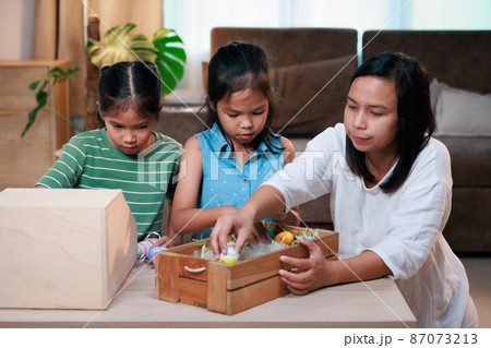 Asian mother and her daughters are decorating easter eggs preparing for Easter at home. Happy family Happy easter Happy holiday. Asian mother and her daughters are decorating easter eggs preparing for Easter at home. Happy family Happy easter Happy holiday. 87073213