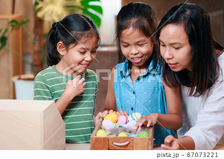 Asian mother and her daughters are playing with baby bunny and decorating easter eggs preparing for Easter at home. Happy family Happy easter Happy holiday. Asian mother and her daughters are playing with baby bunny and decorating easter eggs preparing for Easter at home. Happy family Happy easter Happy holiday. 87073221