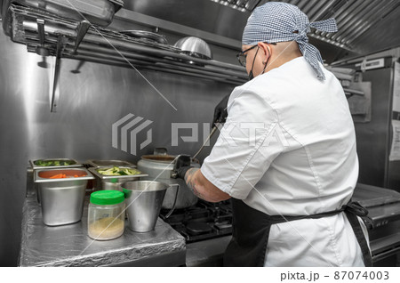 Side view of female chef working in commercial kitchen 87074003