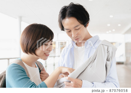 外出先で赤ちゃんをあやす男女 87076058