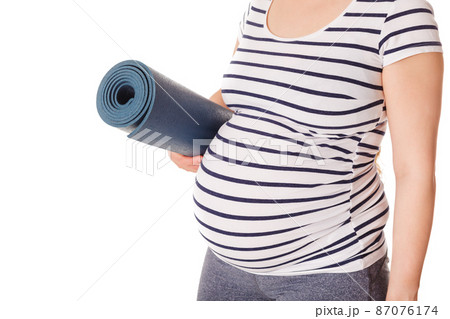Pregnant woman standing with yoga mat 87076174