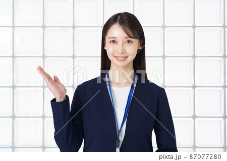案内のポーズをするスーツ姿の女性 87077280