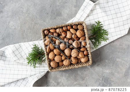 Variety of shelled nuts and nutcracker top view on grey concrete table. 87078225
