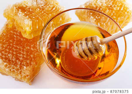 Sweet honey and honeycomb. Healthy organic honey in a bowl and wooden honey dipper. Sweet healthy dessert. 87078375