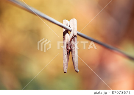 One old retro clothespin wooden on a linen rope. Work on the house, washing, drying linen. Abstract yellow orange autumn background. Concept of outdated forgotten things 87078672