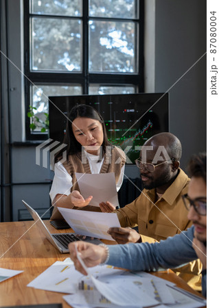 Young confident Asian businesswoman with paper consulting male colleague 87080004
