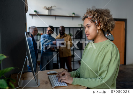Young pretty biracial businesswoman looking at computer screen Young pretty biracial businesswoman looking at computer screen 87080028