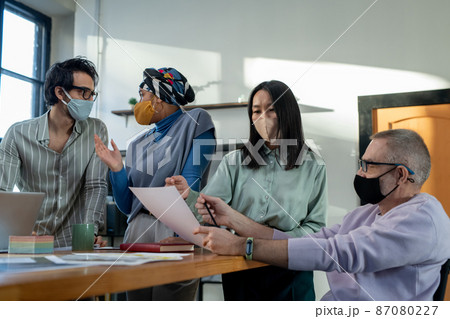 Young Asian female economist and mature businessman discussing paper 87080227