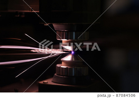 Laser machine cutting sheet of metal with bright sparks closeup 87084506