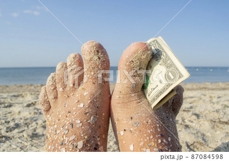 Two bare feet of caucasian woman soiled in sand with shell rock and dollar 87084598