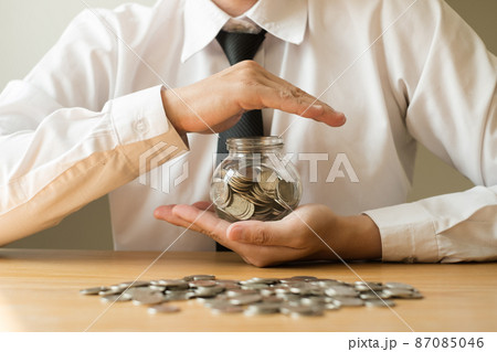 Man's hand protects glass bottles, saves money with coins, steps towards real estate Investment savings concept 87085046