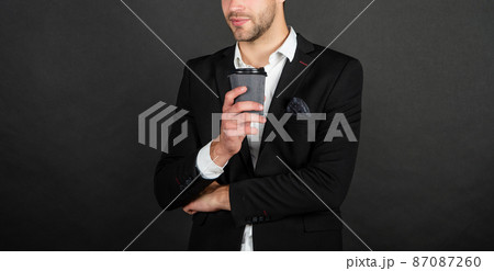 cropped handsome young man in suit with takeaway coffee cropped handsome young man in suit with takeaway coffee 87087260