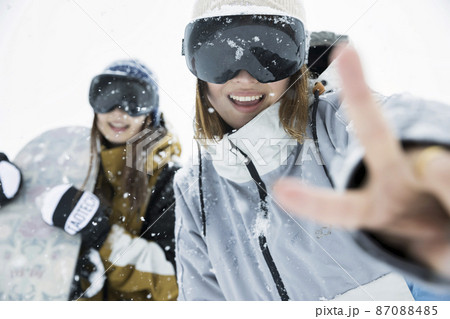 雪の降るスキー場でポーズをするスノボ女子　女子旅 87088485