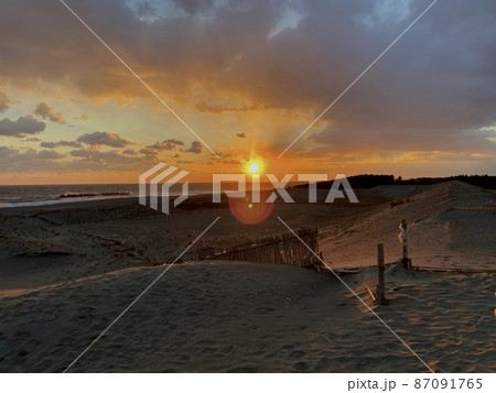 水平線に落ちる夕日の景色と砂丘 水平線に落ちる夕日の景色と砂丘 87091765