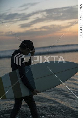 朝の海でサーフィンをする男性 87092985