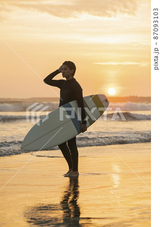 朝の海でサーフィンをする男性 87093103