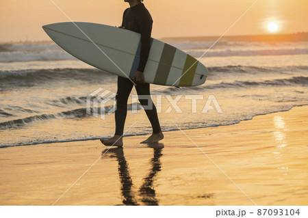 朝の海でサーフィンをする男性 87093104