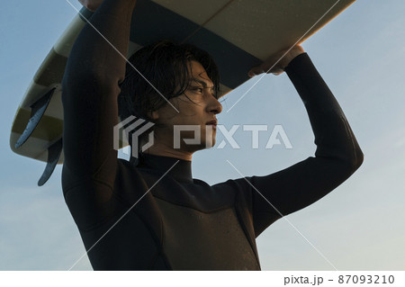 朝の海でサーフィンをする男性 87093210