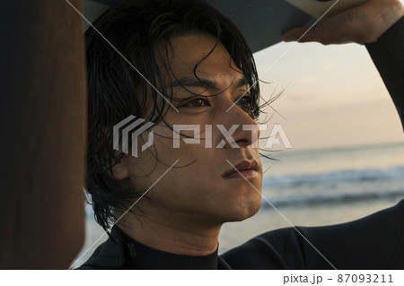 朝の海でサーフィンをする男性 87093211