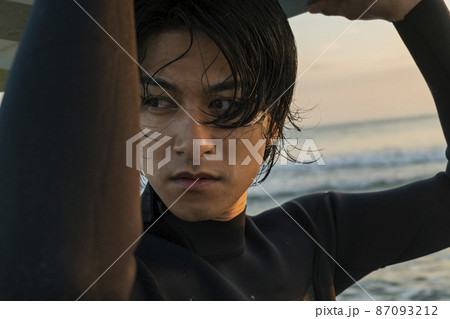 朝の海でサーフィンをする男性 87093212