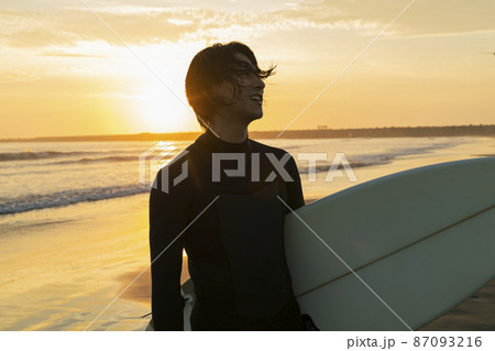朝の海でサーフィンをする男性 87093216