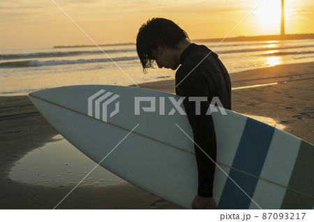 朝の海でサーフィンをする男性 87093217