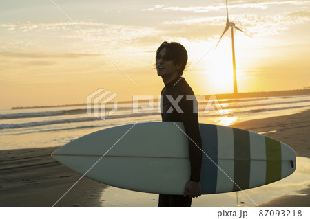 朝の海でサーフィンをする男性 87093218