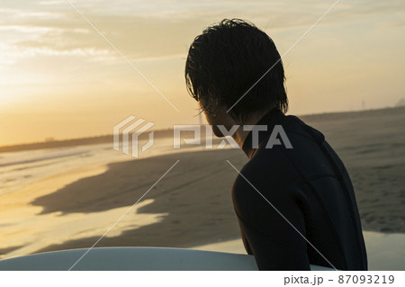 朝の海でサーフィンをする男性 87093219