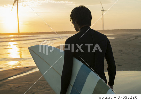 朝の海でサーフィンをする男性 87093220