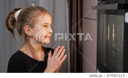 Teenager girl waits for food preparing in stove at home Teenager girl waits for food preparing in stove at home 87095123