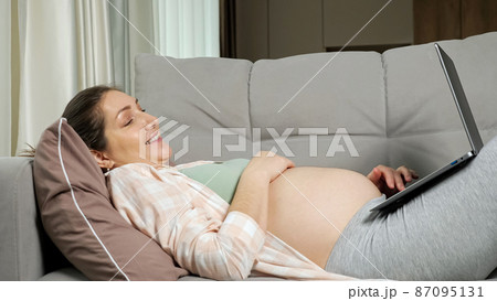 Pregnant mother does online shopping for baby lying on sofa Pregnant mother does online shopping for baby lying on sofa 87095131