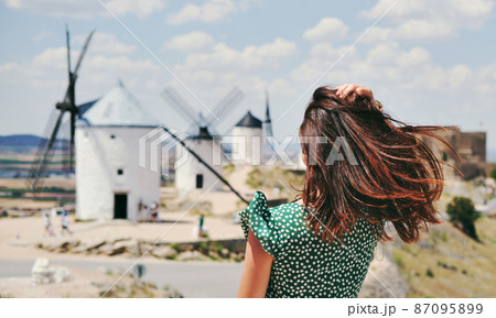Rear view woman posing against windmills in Consuegra town. Spain Rear view woman posing against windmills in Consuegra town. Spain 87095899