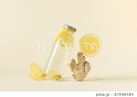 Bottle of infused water with ginger and lemon over light yellow background. Bottle of infused water with ginger and lemon over light yellow background. 87096484