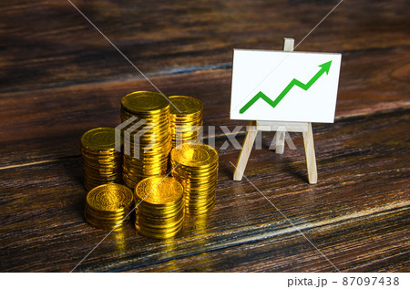 A pile of stacks of coins and an easel with a chart up arrow. Growth in savings and property assets. Enrichment and wealth. Successful investment. Accumulation of pension Funds. Deposit banking. A pile of stacks of coins and an easel with a chart up arrow. Growth in savings and property assets. Enrichment and wealth. Successful investment. Accumulation of pension Funds. Deposit banking. 87097438