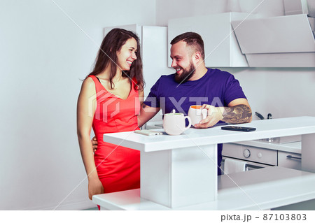 Breakfast in apartment of young couple who drink coffee and smile. 87103803