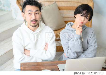 パソコンを見ながら腕を組んで悩むカップル 87105938