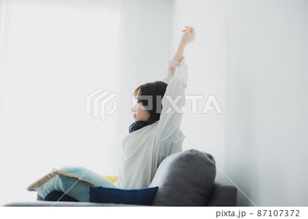 ソファで伸びをする女性 87107372