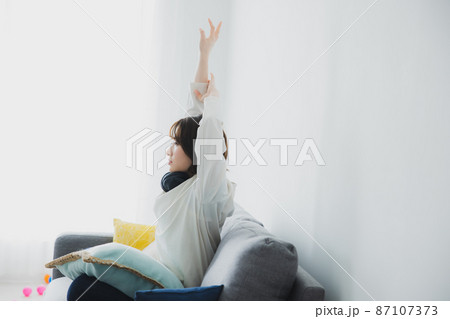 ソファで伸びをする女性 87107373