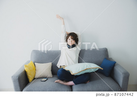 ソファで伸びをする女性 87107442