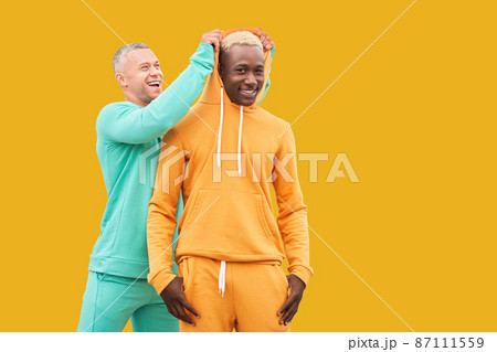 Multi ethnic friends. Two men different color black African-American ethnicity and white Caucasian ethnicity standing isolated yellow background Multi ethnic friends. Two men different color black African-American ethnicity and white Caucasian ethnicity standing isolated yellow background 87111559