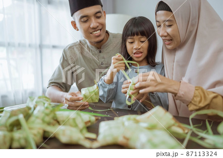 kid with her parent making a ketupat at home 87113324