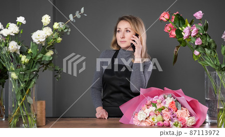 Florist informs customer about composed flowers bouquet Florist informs customer about composed flowers bouquet 87113972
